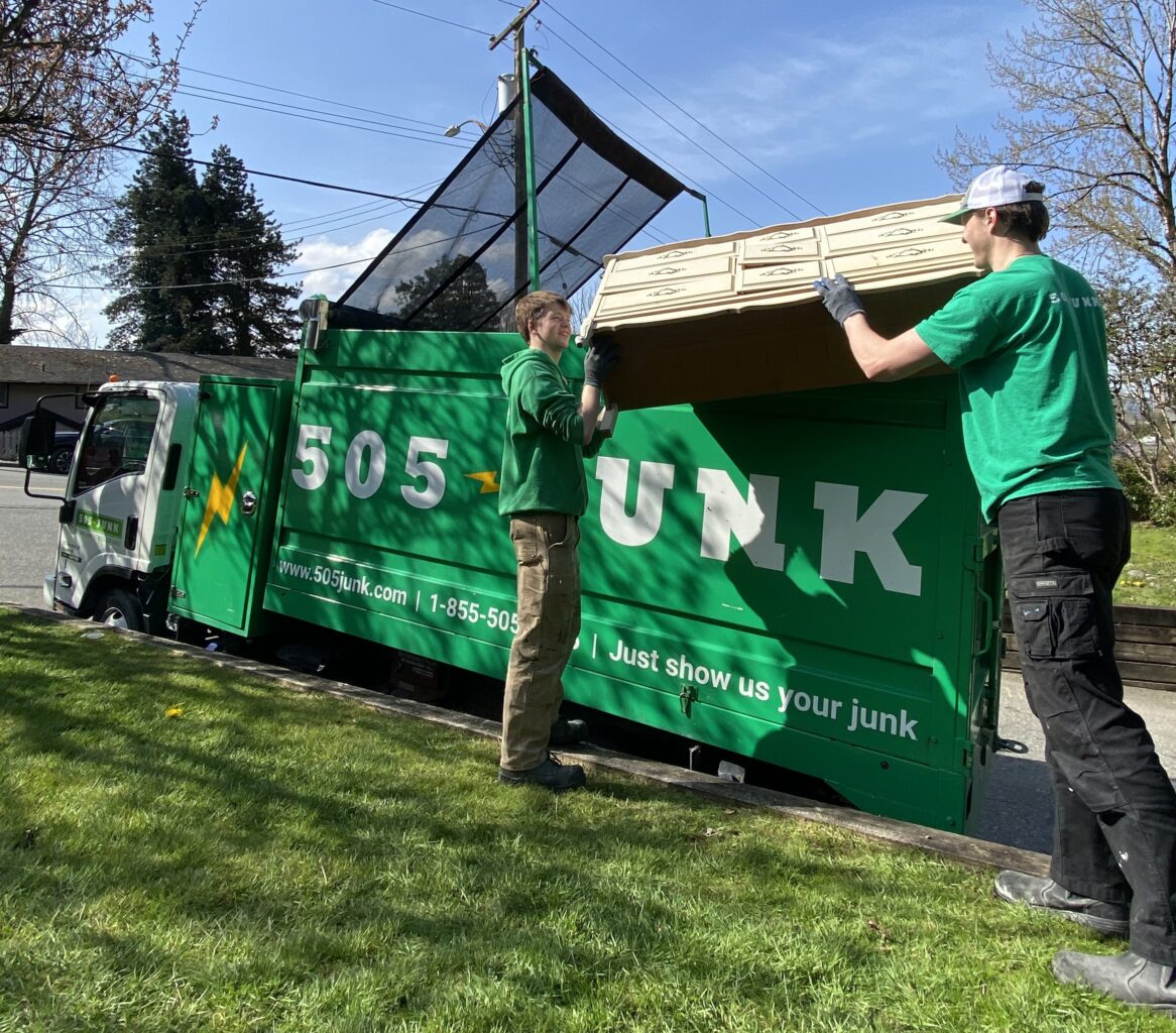Two 505-Junk employees putting an old dresser into the back of the truck during a furniture removal in Coquitlam.