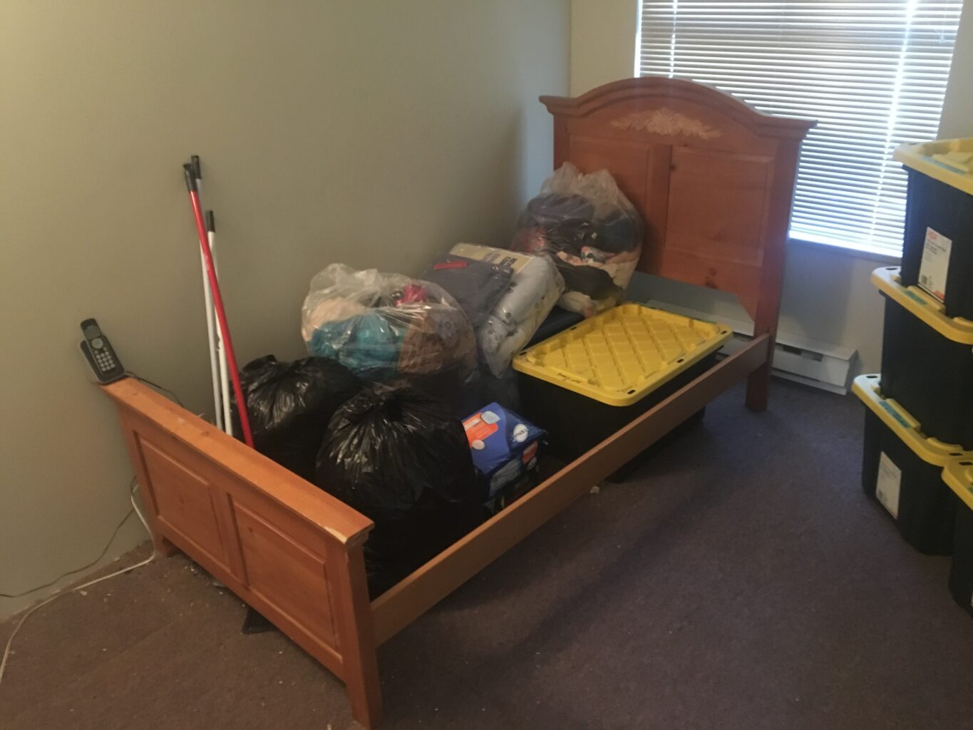 A bedroom with boxes and bags in a bed frame all cleaned up after a hoarding removal in White Rock. 