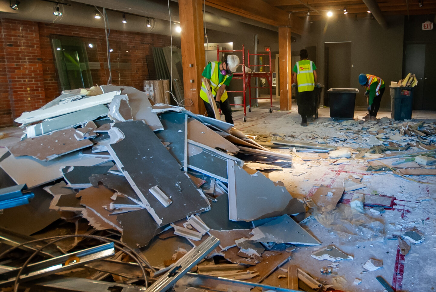 A pile of drywall in an office building after demo. Two 505-Junk employees are sorting through the pile  to prepare for the drywall removal. 