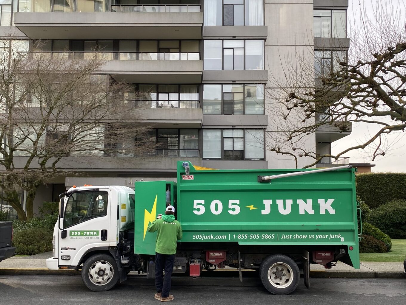 A 505-Junk truck parked in front of an apartment building during a strata junk removal pickup.