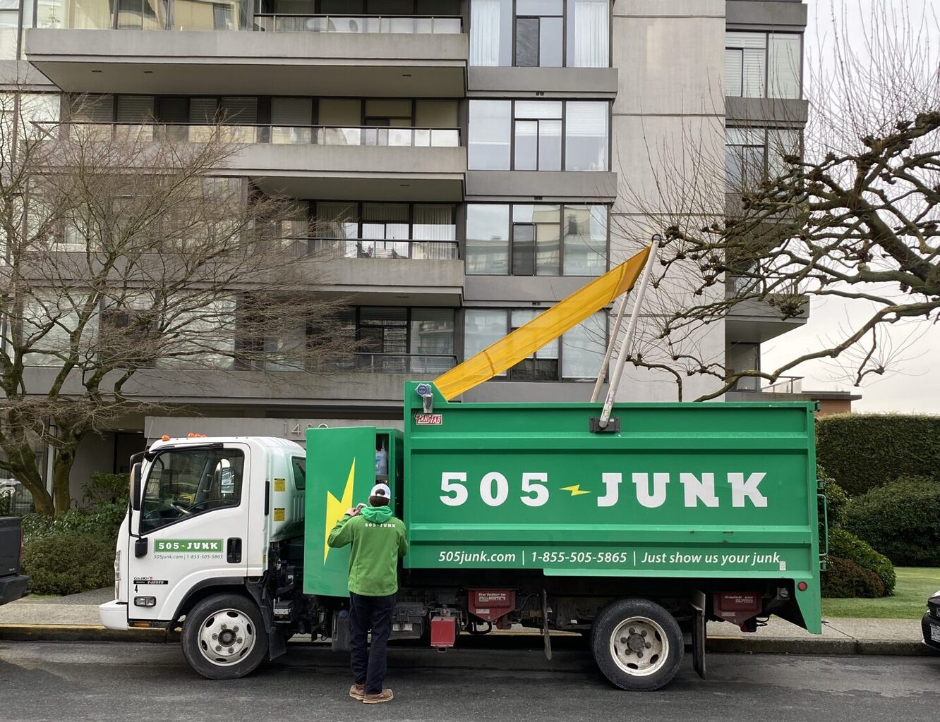 A 505-junk truck parked outside an apartment building during a junk removal for a move out.