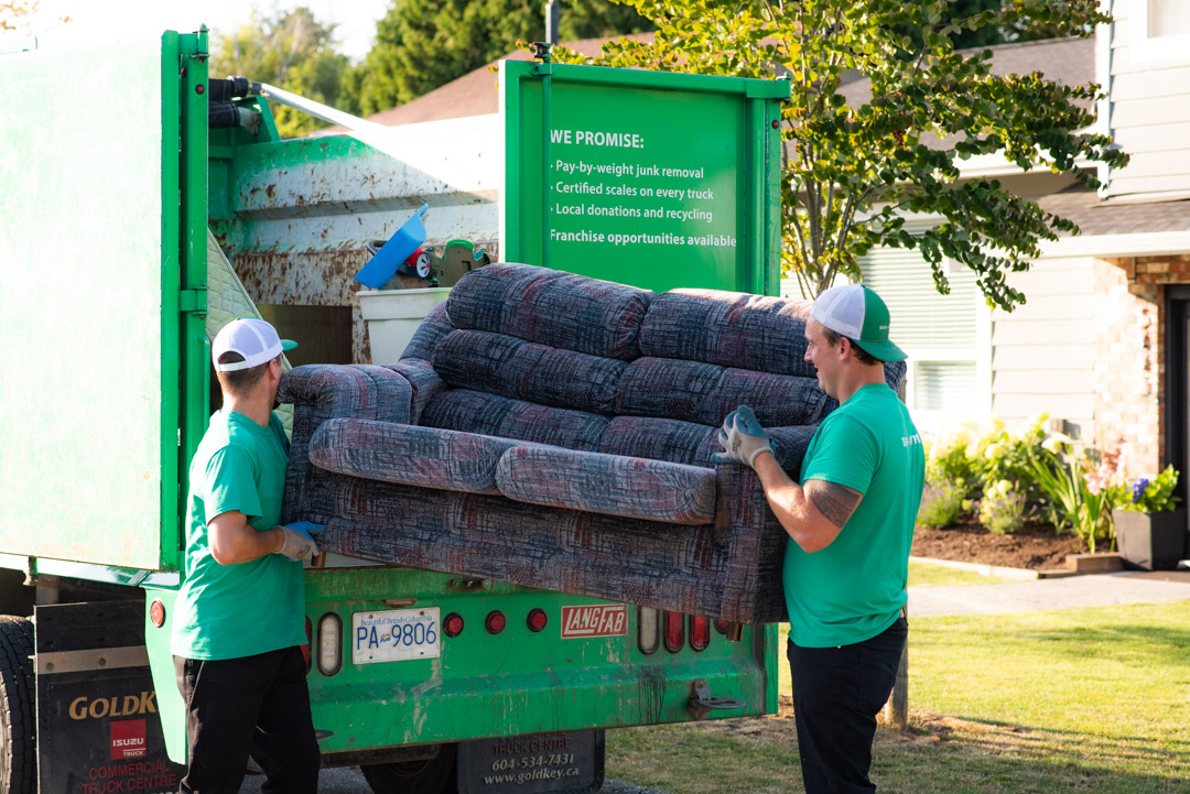 Two 505-Junk employees loading a sofa into the truck during a couch removal in North Delta. 