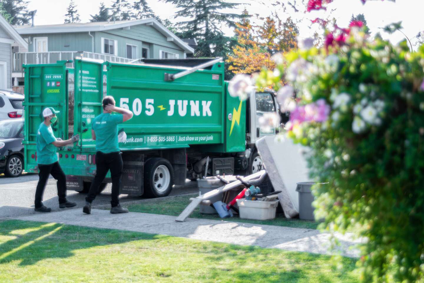 Spring Cleaning Tips from 505-Junk. Junk truck parked with 2 young people loading and spring flowers in the foreground. 