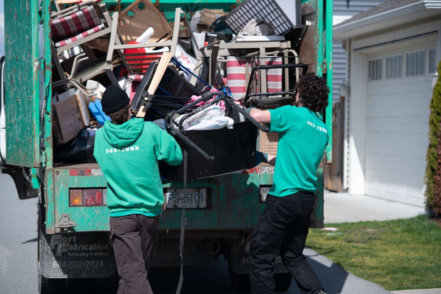 Two 505-Junk employees loading unwanted items into the truck during a rubbish removal in Delta.