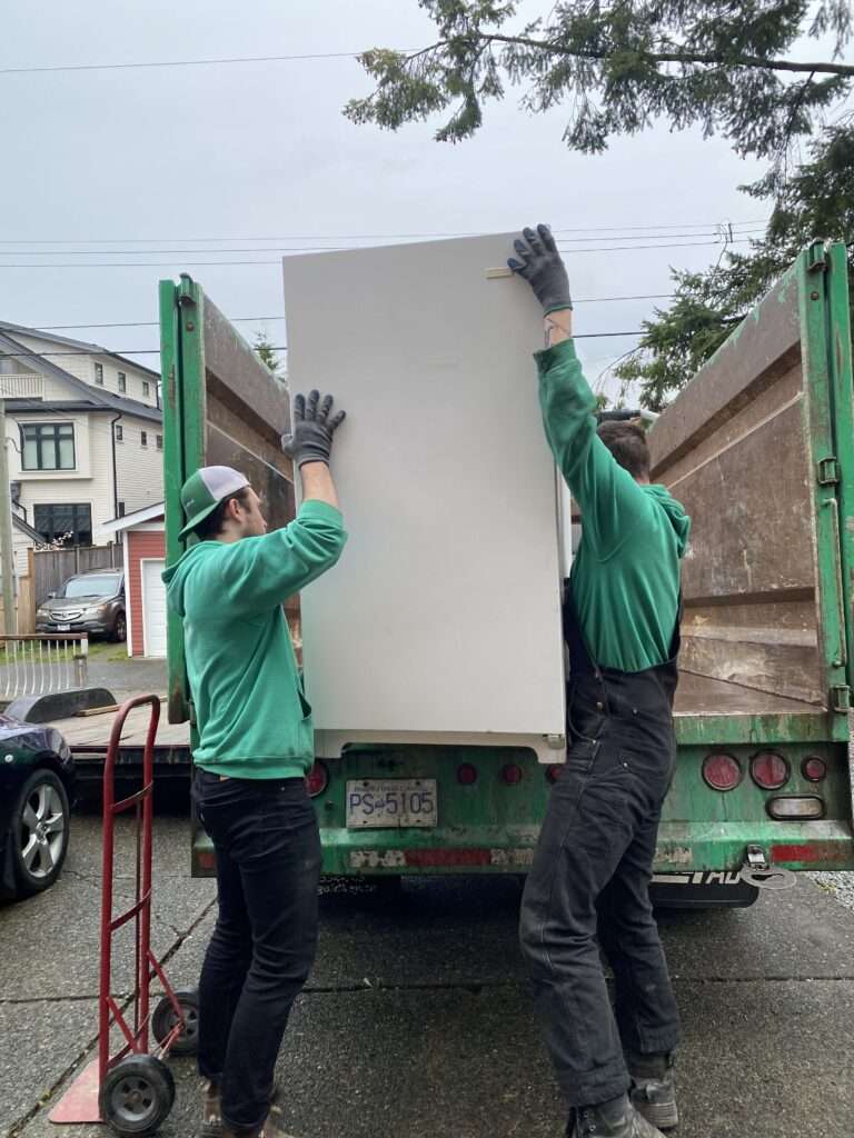 Our team members loading a fridge into the truck during an appliance removal in Burnaby.