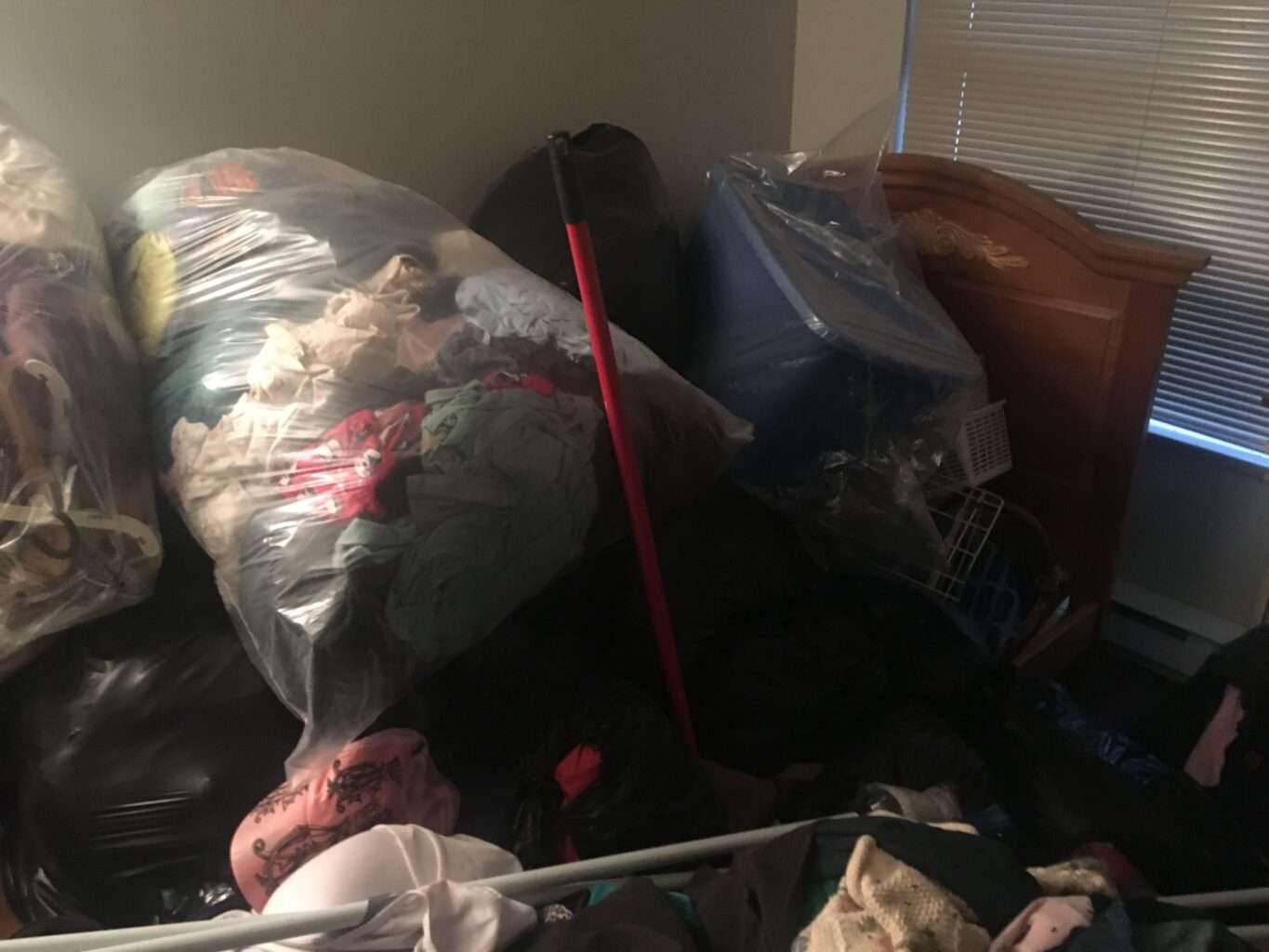 The bedroom is full of bags and clothing before a hoarding removal in Richmond. We also do this for hoarding removal in Burnaby