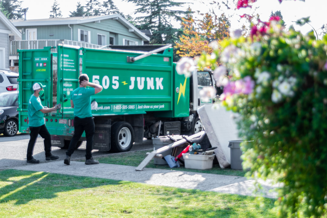Two 505-Junk employees loading a pile of junk into the truck during a rubbish removal pickup in Port Moody.