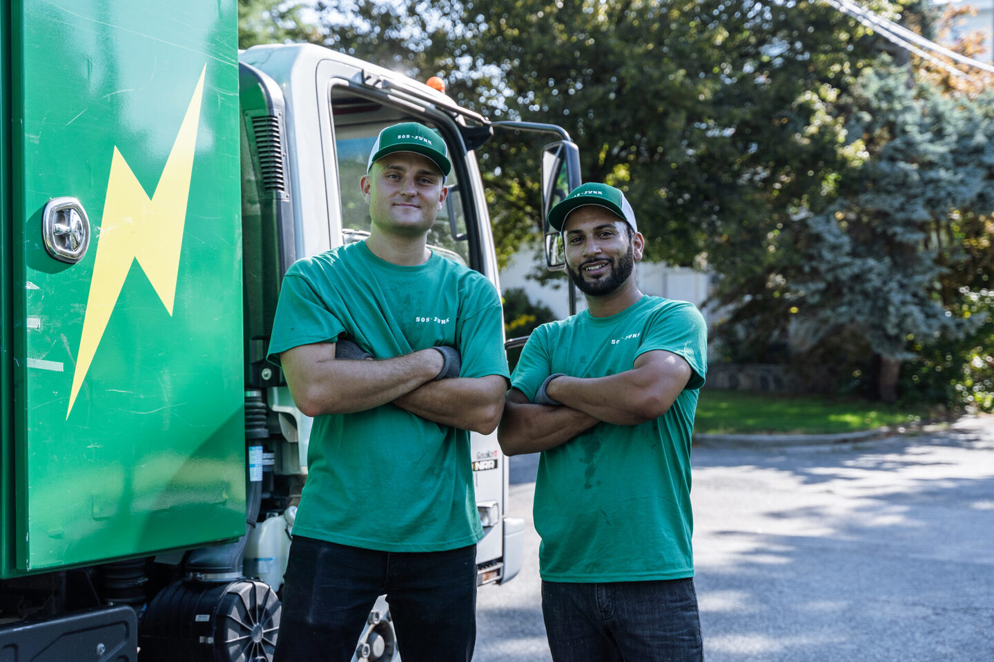 Two 505-Junk employees standing in front of the junk truck smiling with their arms folded after a couch removal in Port Moody.