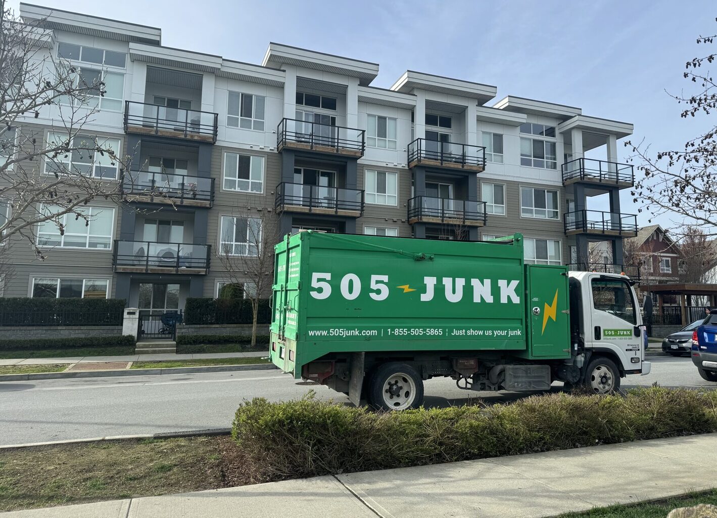 A 505-Junk truck parked in front of an apartment complex during a strata junk removal pickup.