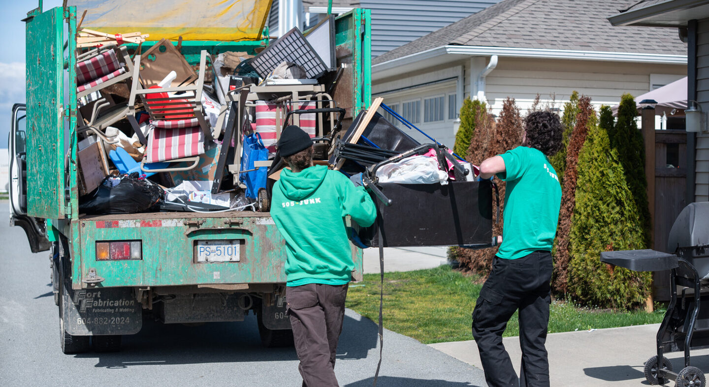 Two 505-Junk employees loading the truck with a black box full of material during a downsizing clearout.