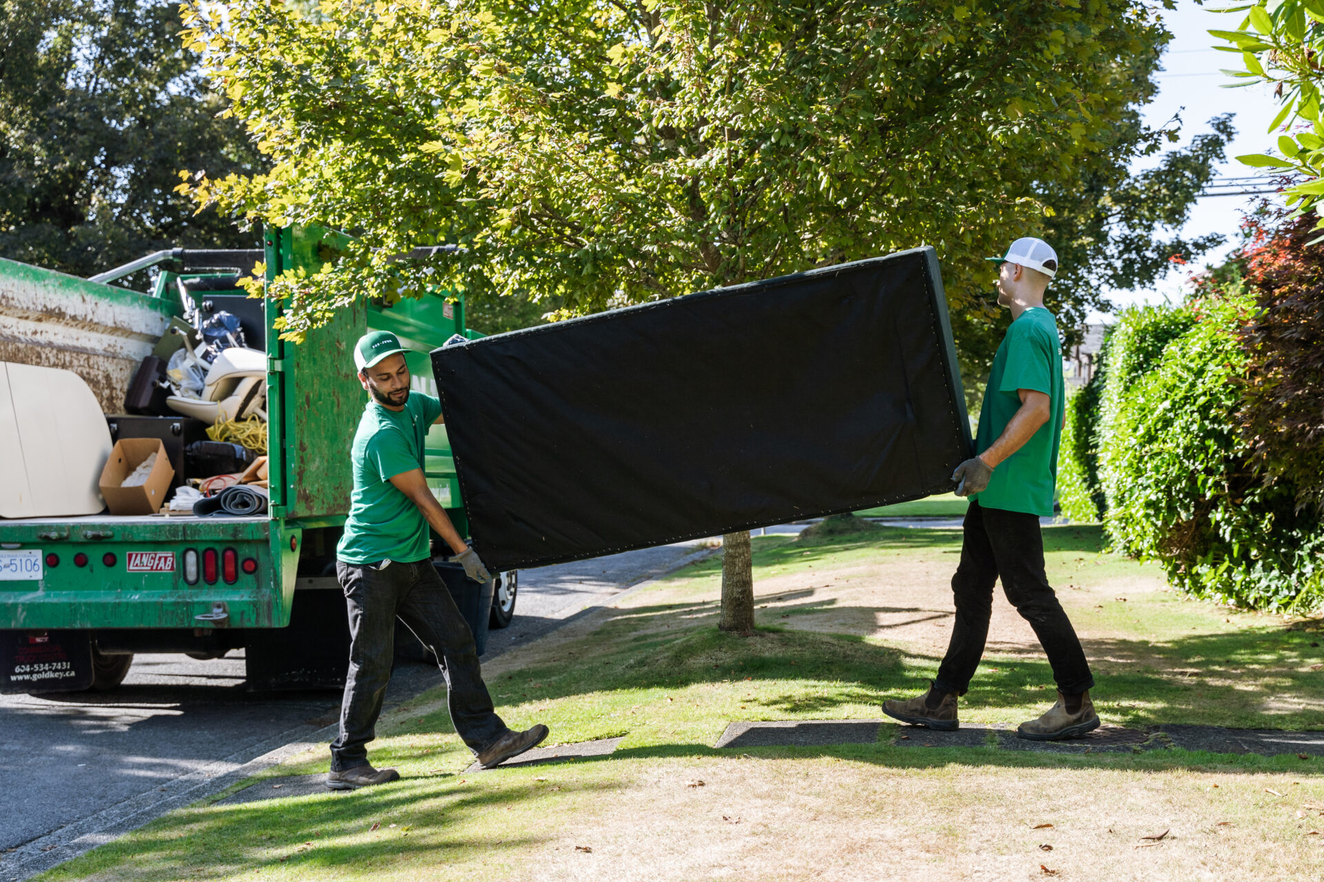 Two 505-Junk employees carrying an old sofa to the truck during a couch removal in North Delta.